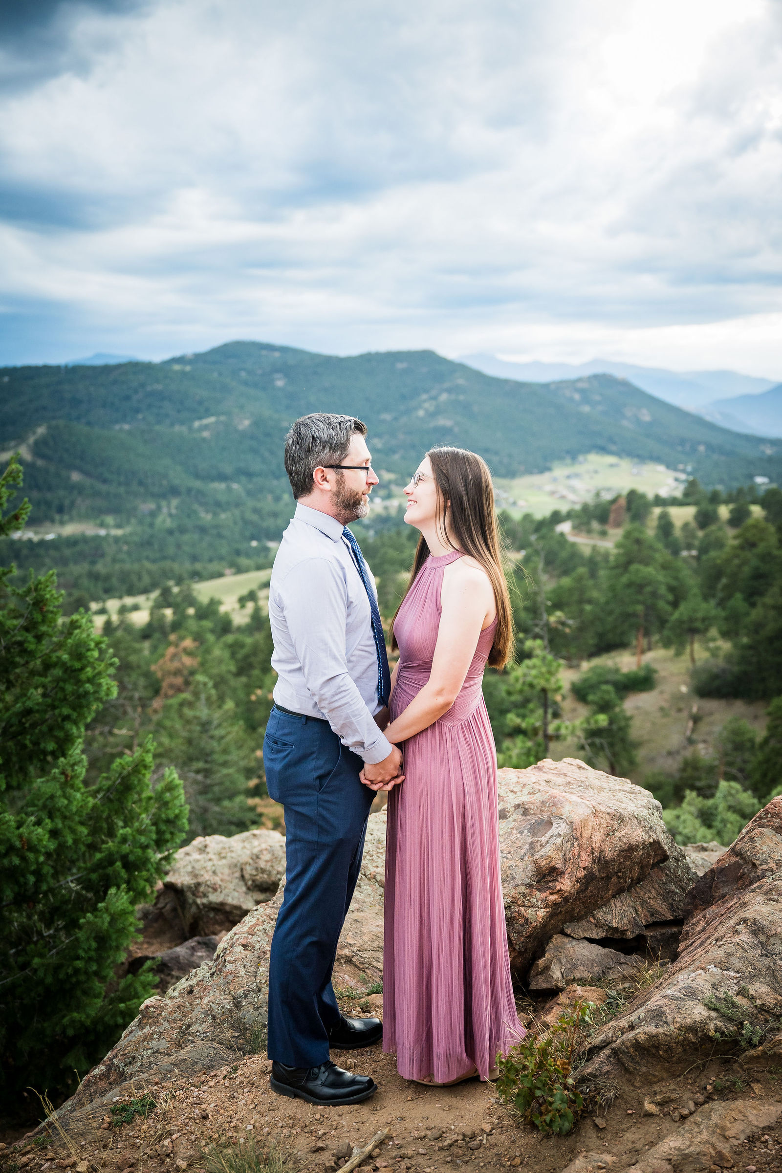 Engaged couple in a dusty rose maxi dress and a light blue shirt with navy trousers in the Colorado mountains