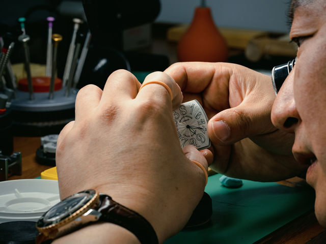 Meridian watchmaker inspecting a watch dial through a loupe
