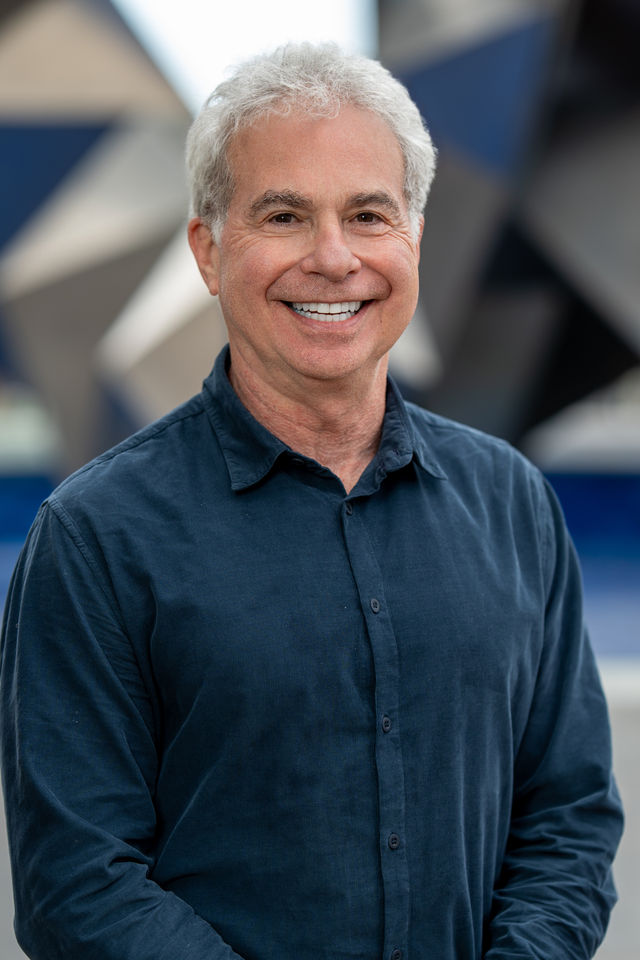 Headshot of a smiling executive in a navy shirt, photographed by Dodi Images