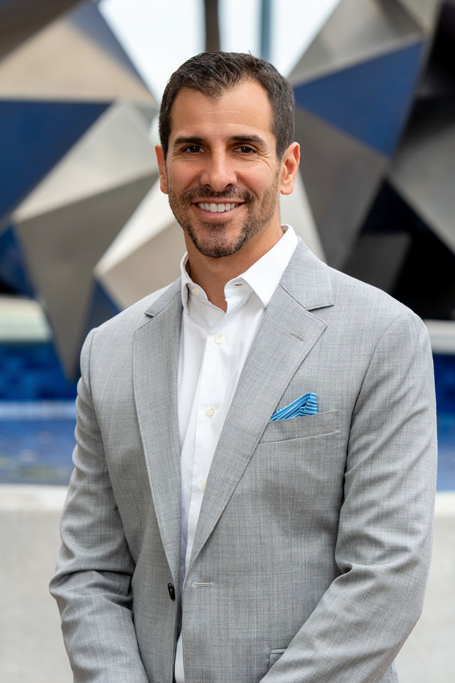 Professional headshot of a smiling man in a gray blazer by Dodi Images, conference headshot lounge photographer in California