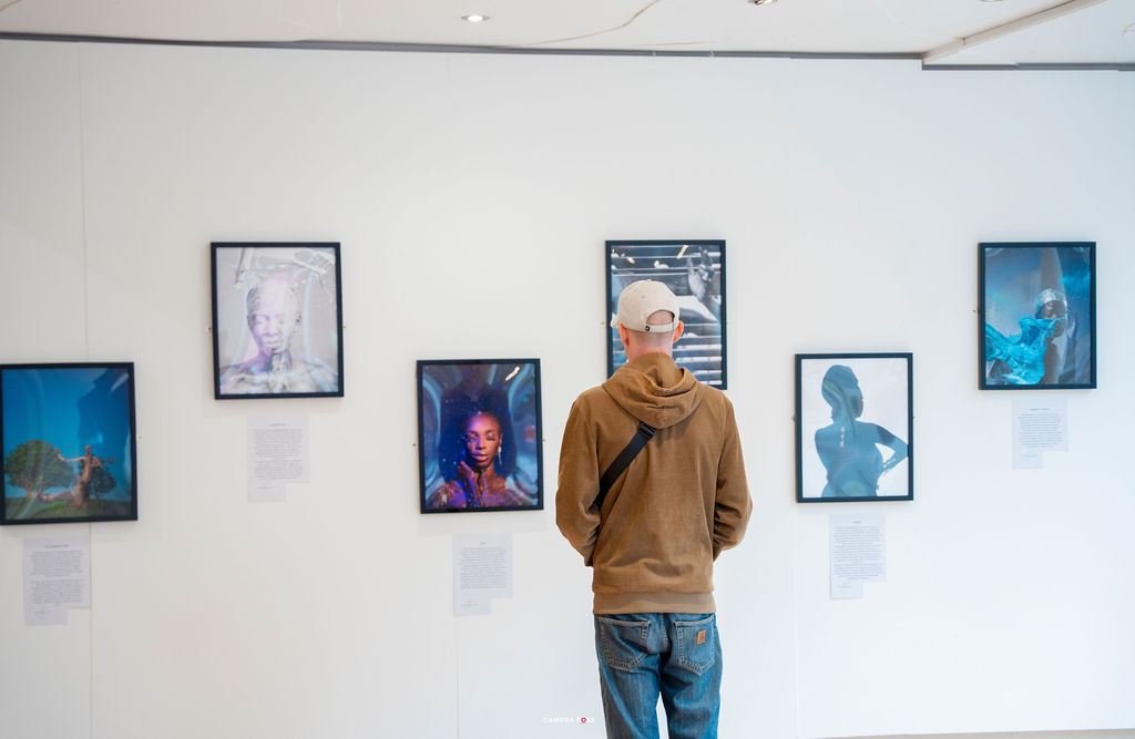 A visitor in a hooded top standing close to a framed photograph, reading the wall label