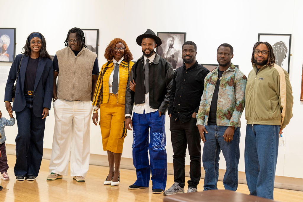 A large group of friends and guests standing in a line together in the gallery, with John Lekan in the fedora among them