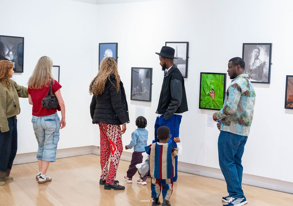 Visitors with a young child looking at framed photographs in the white-walled gallery at LCB Depot