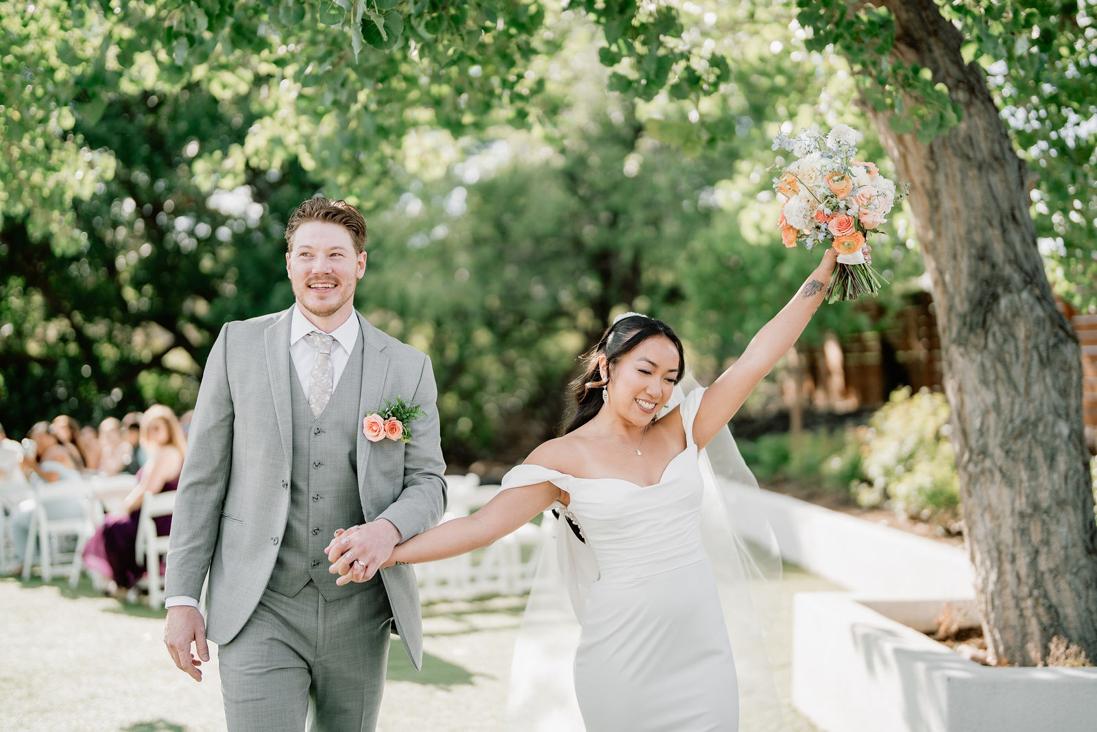 Newlyweds walking back up the aisle, bouquet raised, at Creekside Terrace in Colorado.