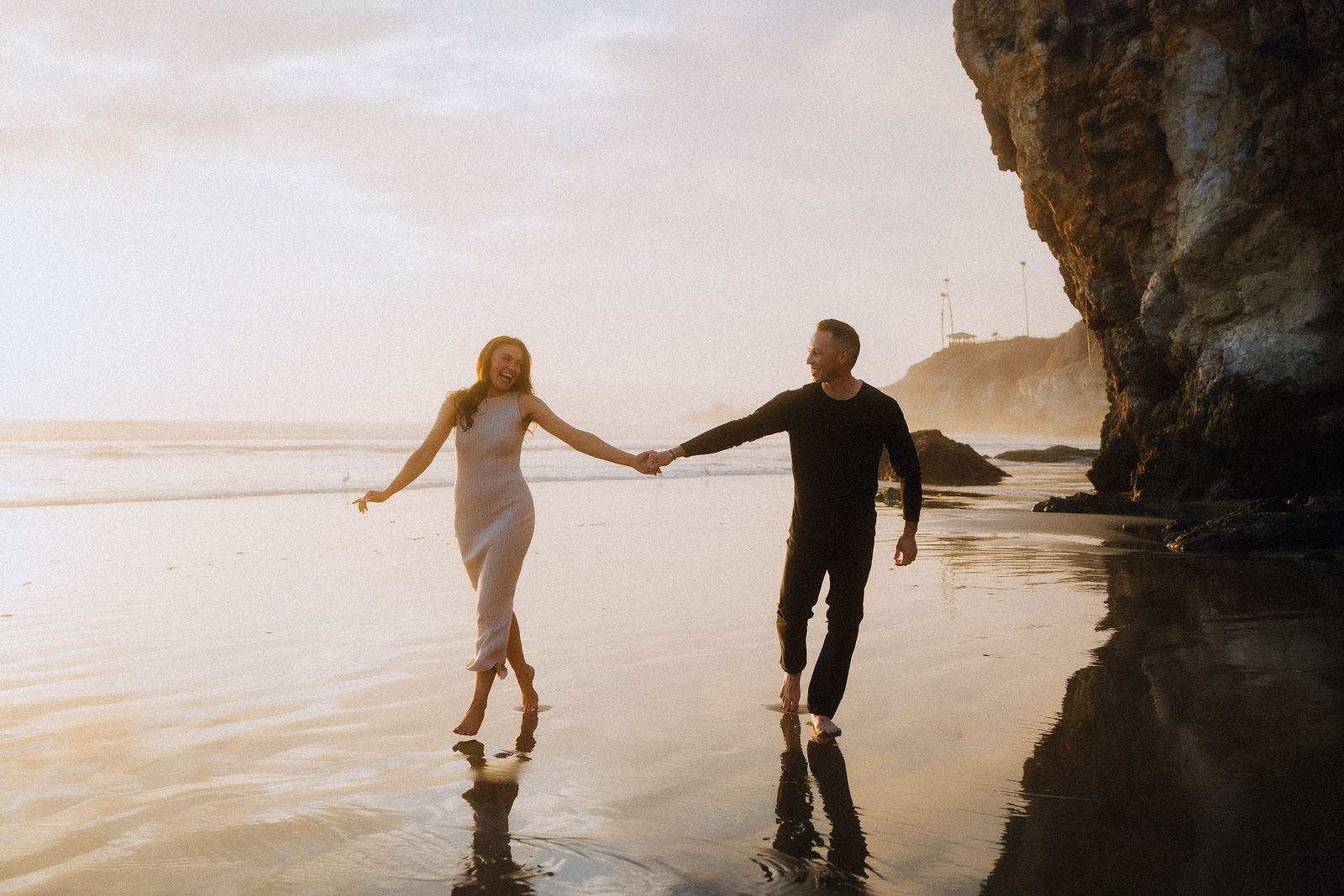 A couple walking the beach together after a surprise proposal.