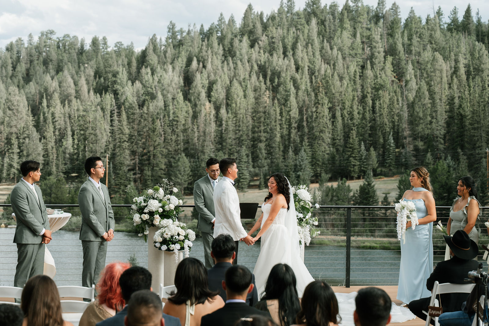 A couple exchanging vows beside a forest and lake at Mountain View Ranch in Colorado.
