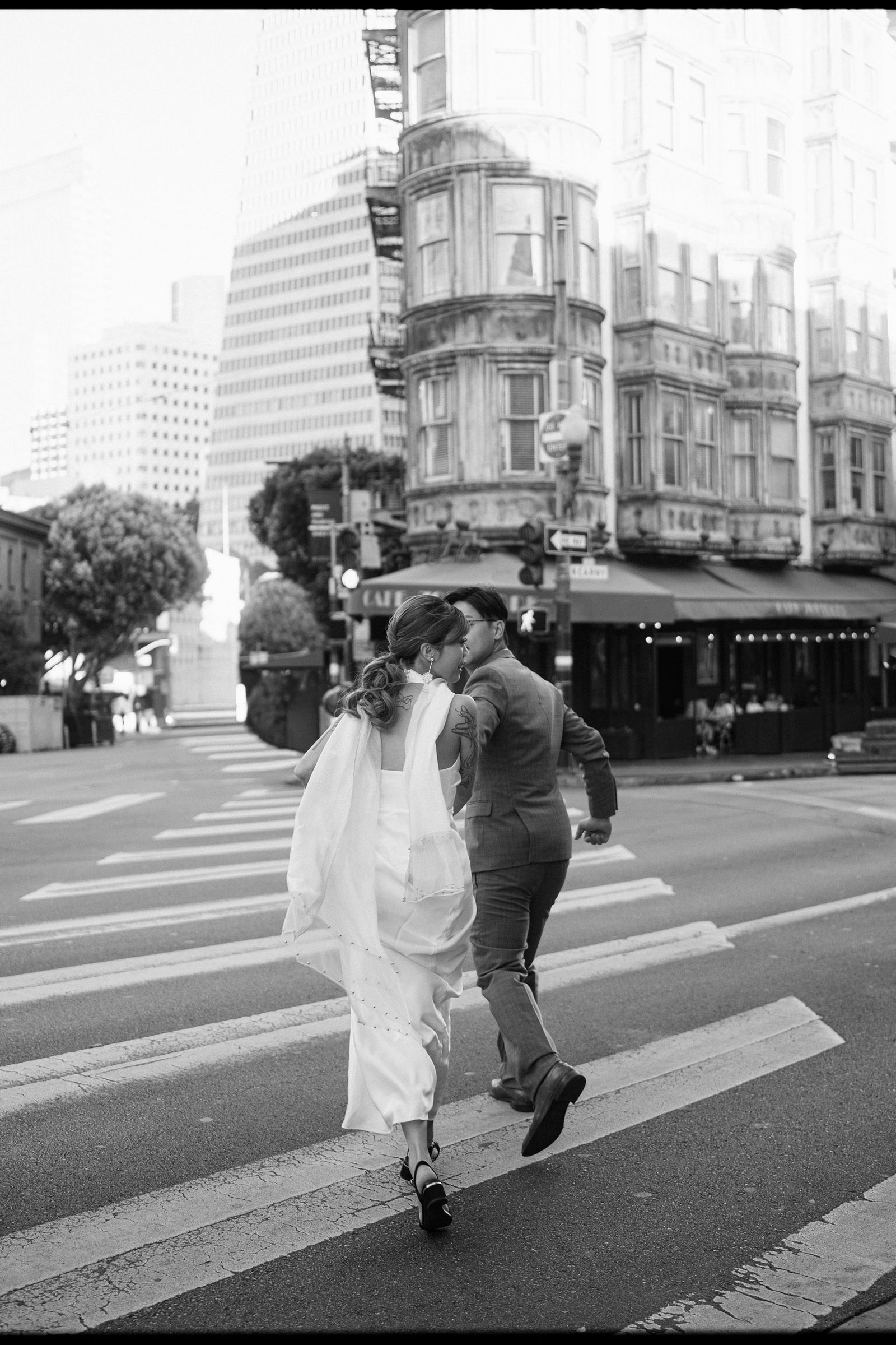 A newly married couple running across a San Francisco street during their elopement.