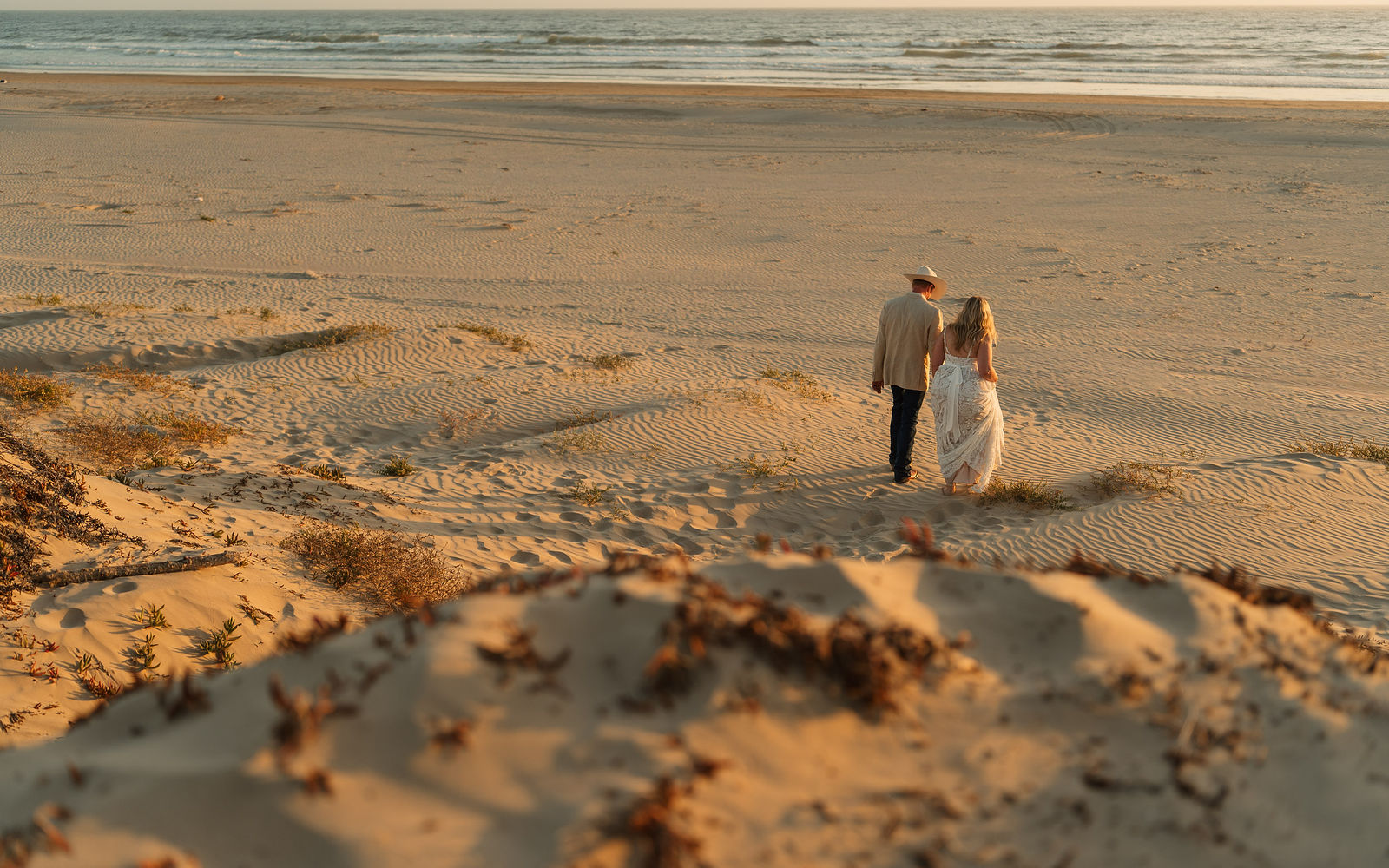 A couple walking through the sand dunes at Grover Beach during their elopement.