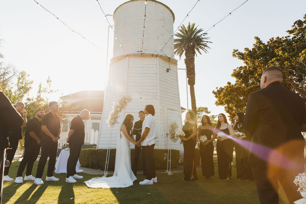Wedding ceremony beside a white lighthouse in golden light