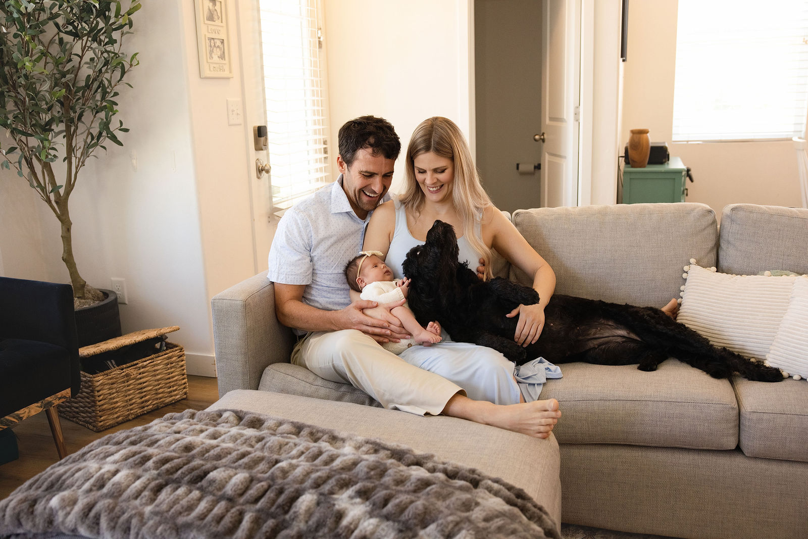 Lifestyle newborn photography in Salt Lake City capturing parents holding baby near living room window