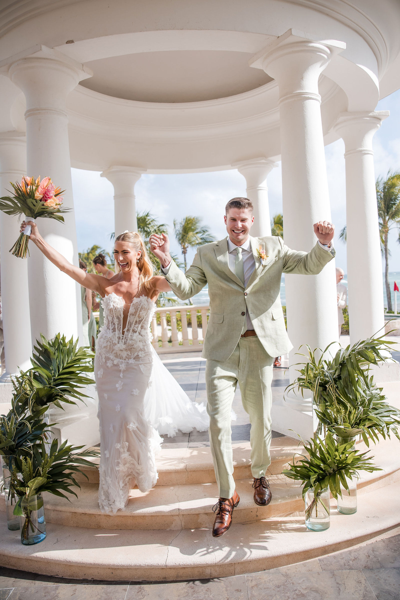A couple celebrating beneath a colonnade after their beachfront ceremony