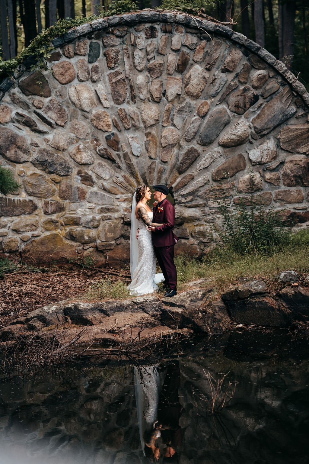 Kristin and Mike kissing at the circular stone arch with its water reflection