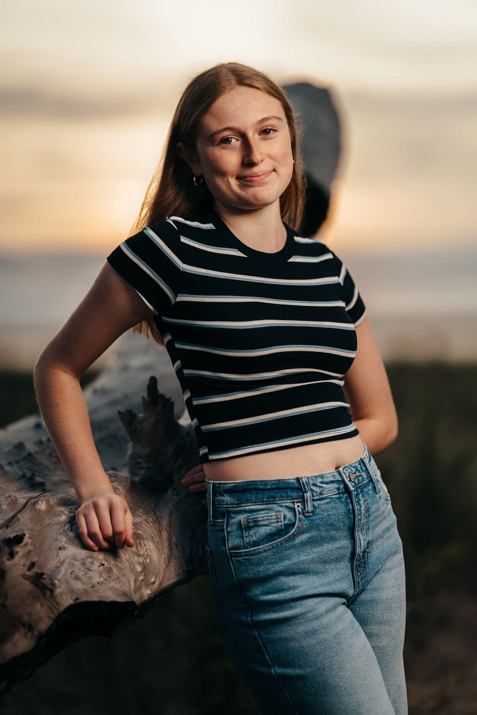 Arianna leaning on driftwood during her senior portrait session