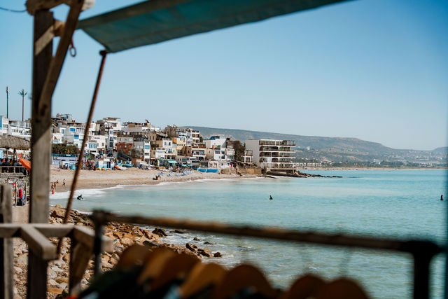 Taghazout beach and village seen through a shaded foreground