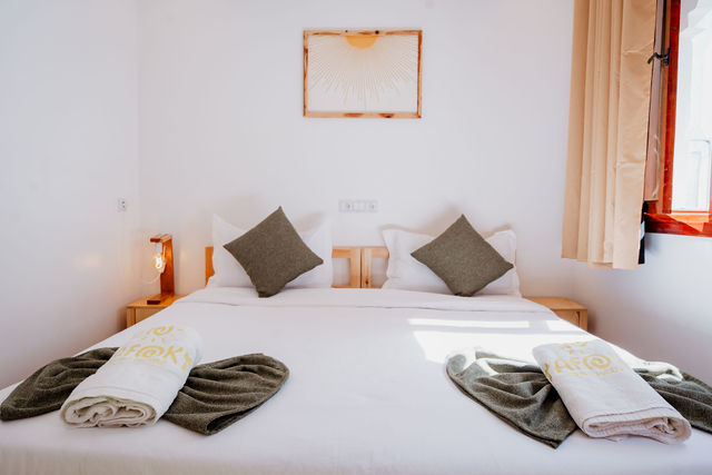 A made bed with white linens and Tafokt towels in a sunlit bedroom