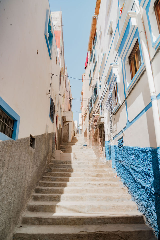 Sunlit steps between white and blue buildings in Taghazout