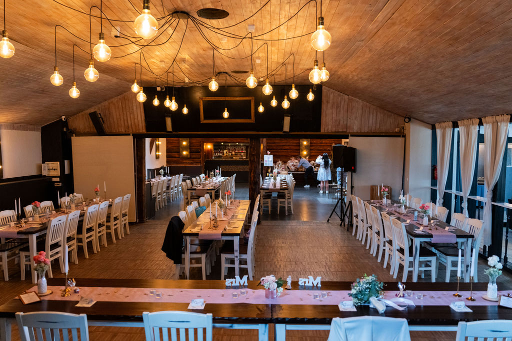 Festsaal mit Mr-and-Mrs-Tischdeko und Bar im Hintergrund, Eventlocation Richtershorn am See Berlin