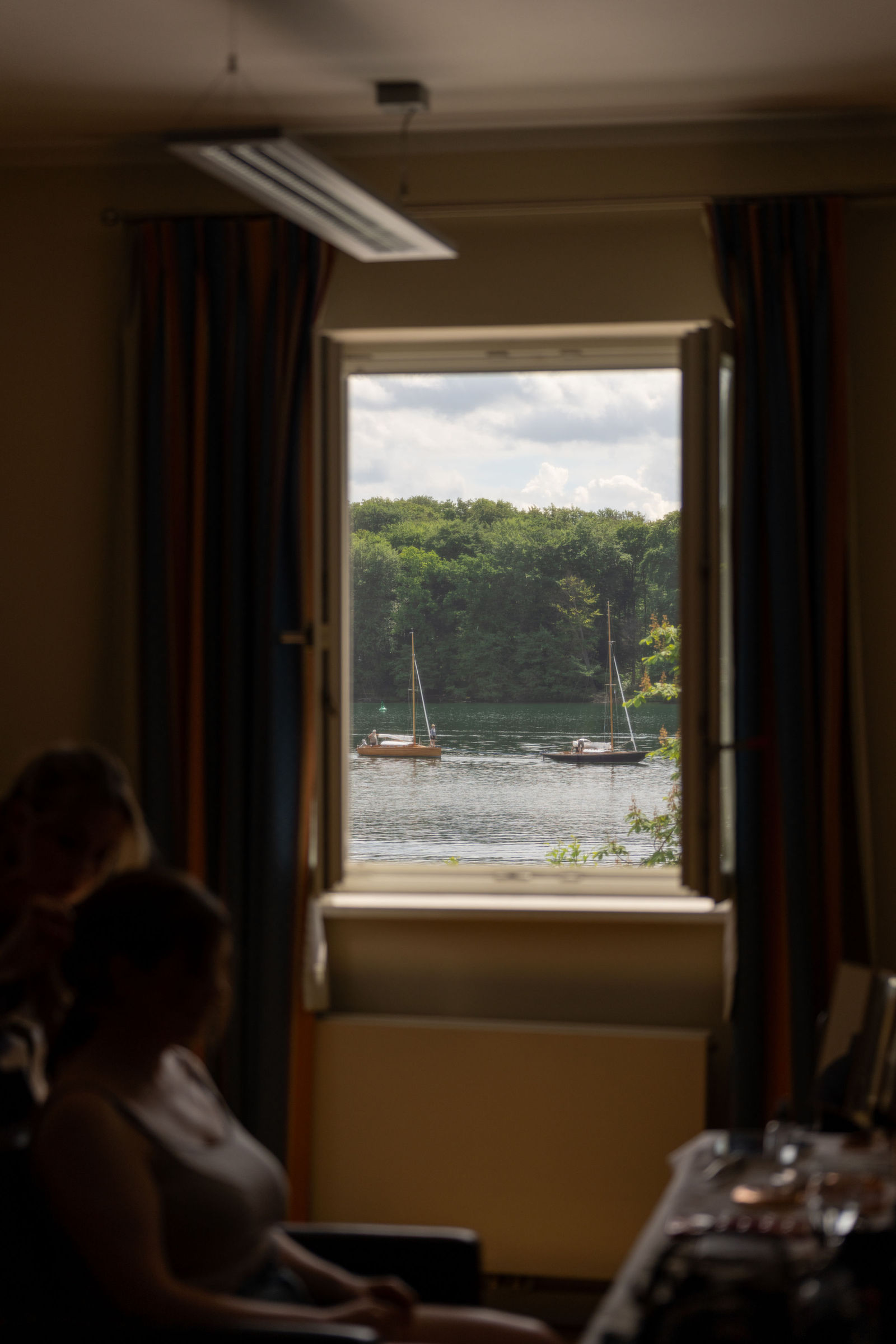Braut beim Styling am geöffneten Fenster mit Blick auf Segelboote auf dem Werbellinsee, Café Wildau