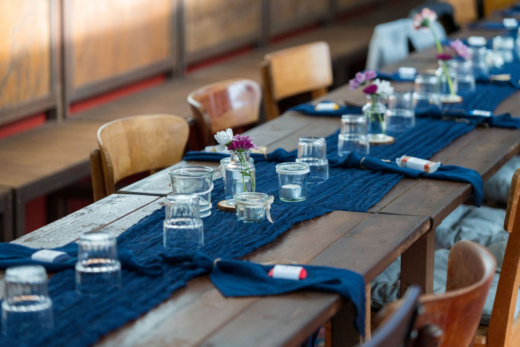 Tischdekoration mit blauem Läufer und Kerzen bei einer Hochzeit in der Oberhafenkantine Berlin