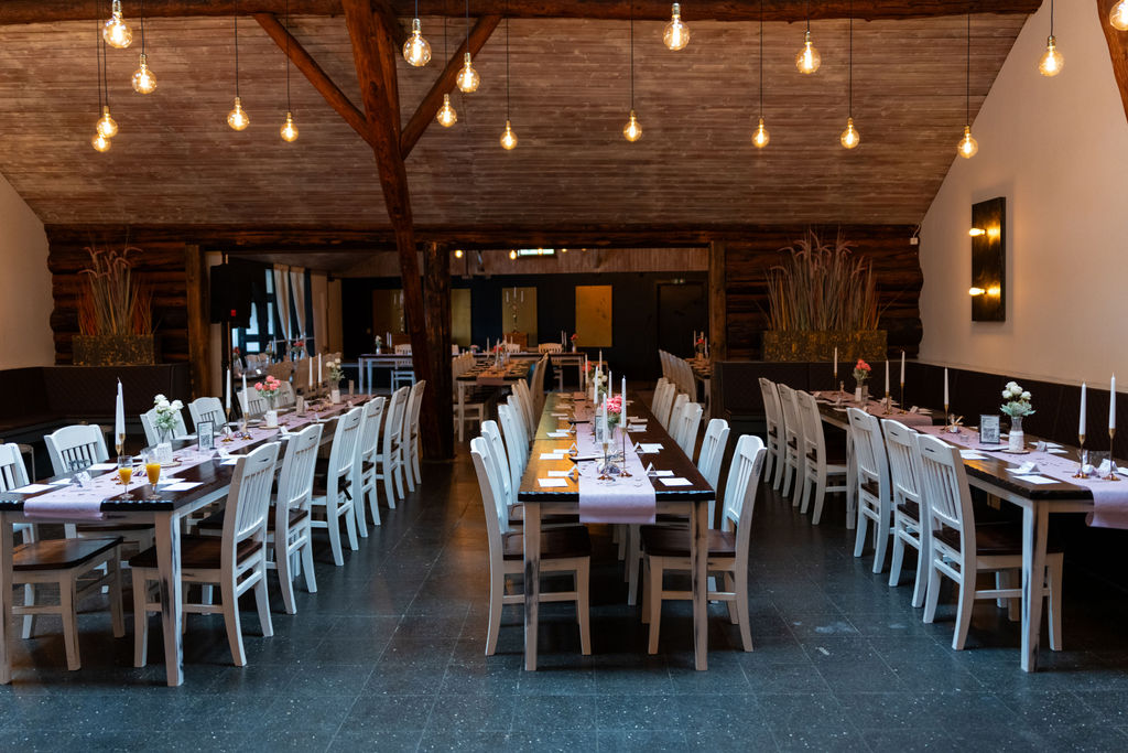 Symmetrischer Blick durch den Festsaal des Richtershorn am See mit langen Hochzeitstafeln
