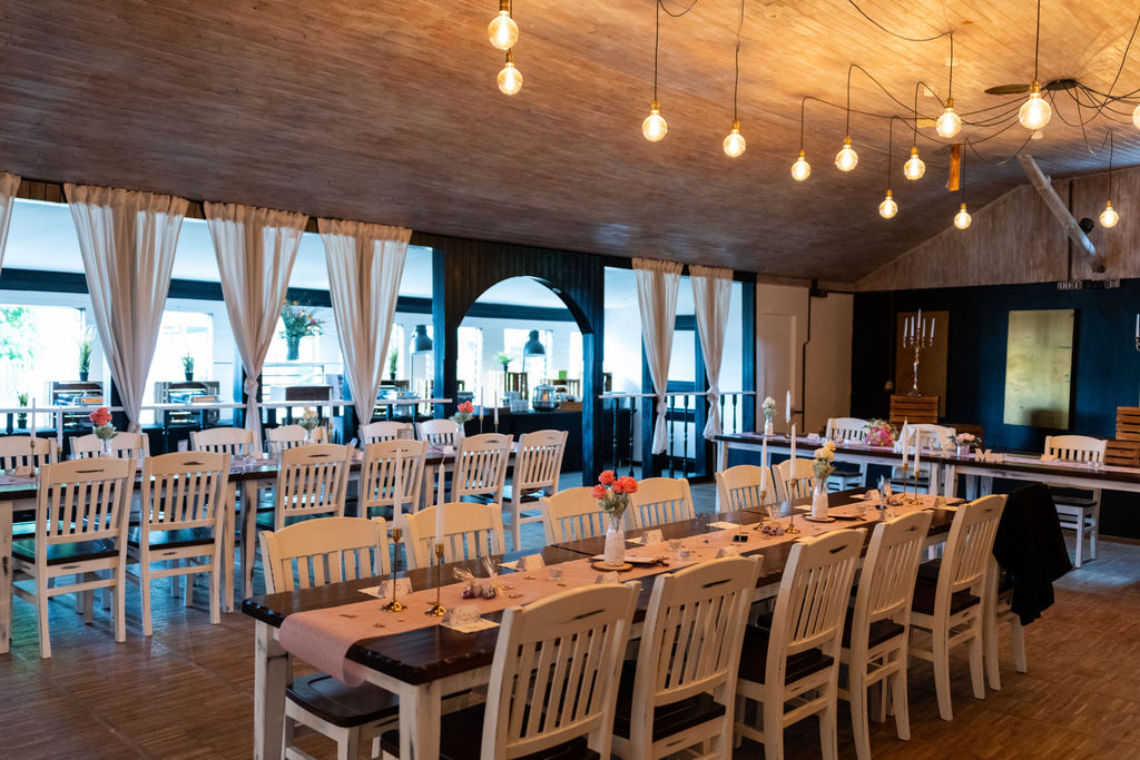 Festsaal mit gedeckter Hochzeitstafel und Lichterketten im Richtershorn am See, Hochzeitslocation Berlin Grünau