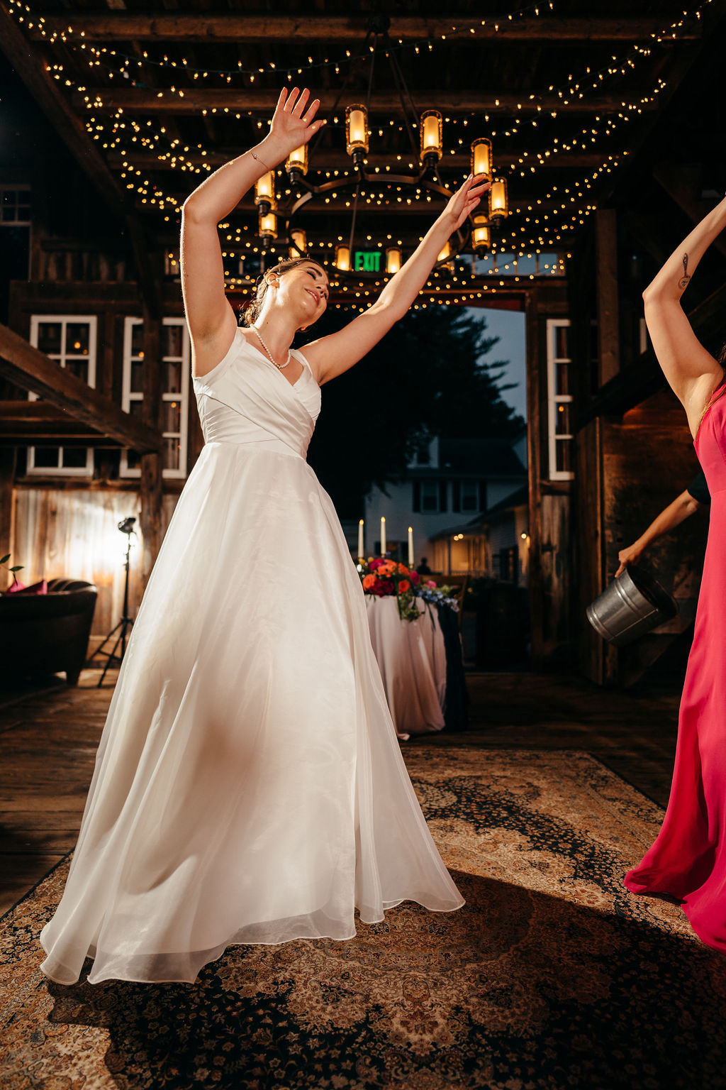 Bride dancing with her arms raised in the barn