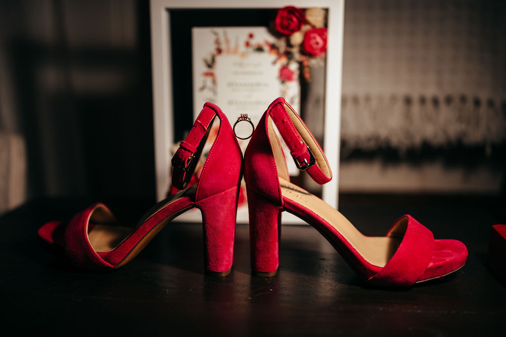 Red high-heeled wedding shoes on a dark surface