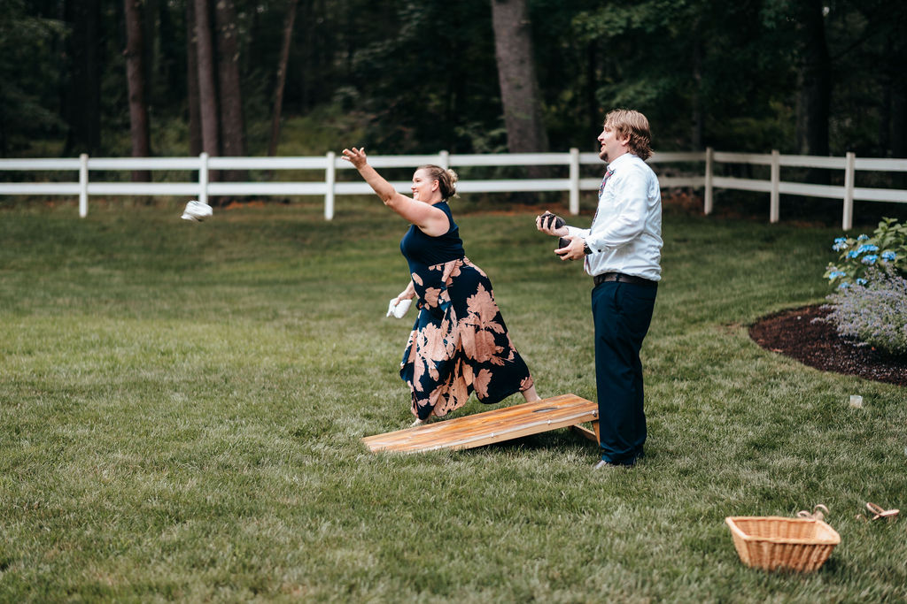 Guests playing cornhole on the lawn during cocktail hour