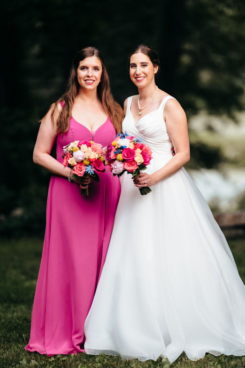 Bride posing with a bridesmaid in a pink dress