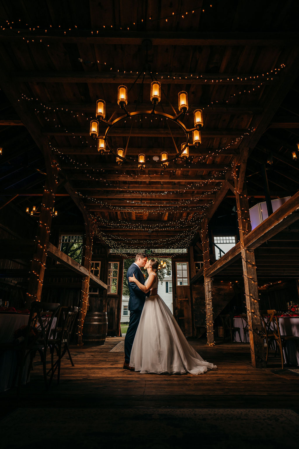 Couple embracing under a chandelier in the barn