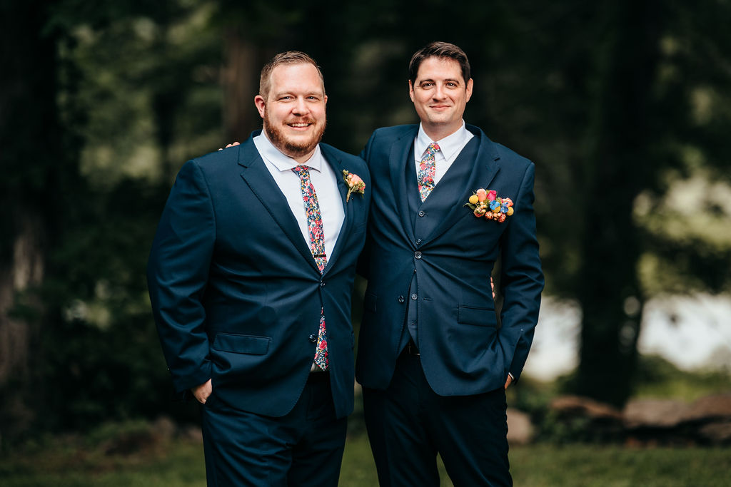 Two groomsmen in navy suits posing together