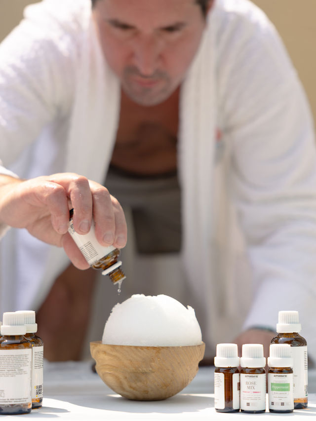 Dripping essential oil onto an aromatherapy snowball resting in a wooden bowl