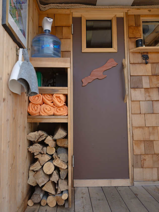 Six rolled orange terry cloth towels stored on the shelf inside the mobile sauna
