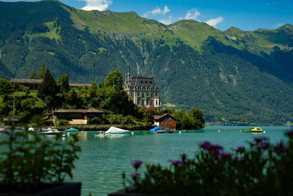 A castle on a wooded peninsula in a turquoise alpine lake