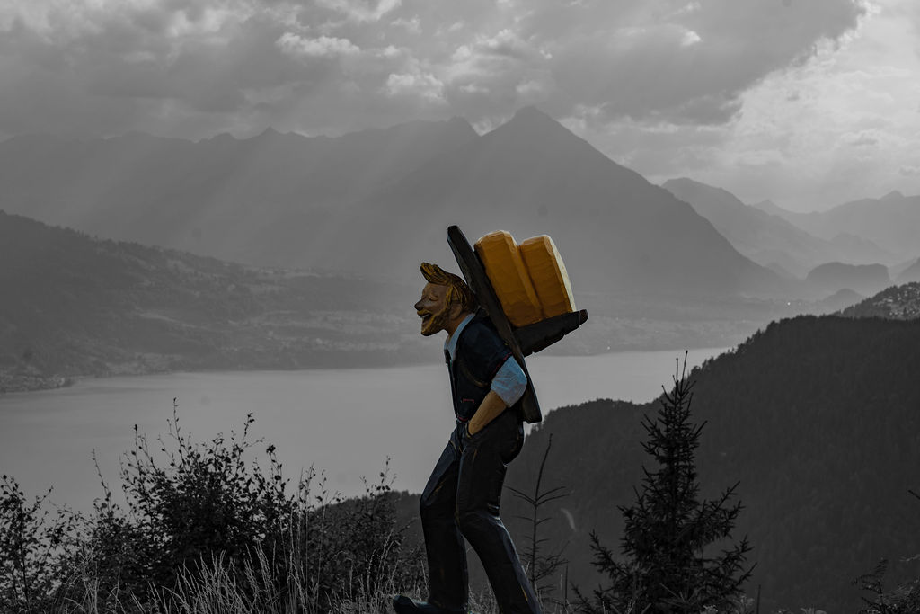 A hiker with a yellow backpack above a lake, in black and white, Jungfrau region