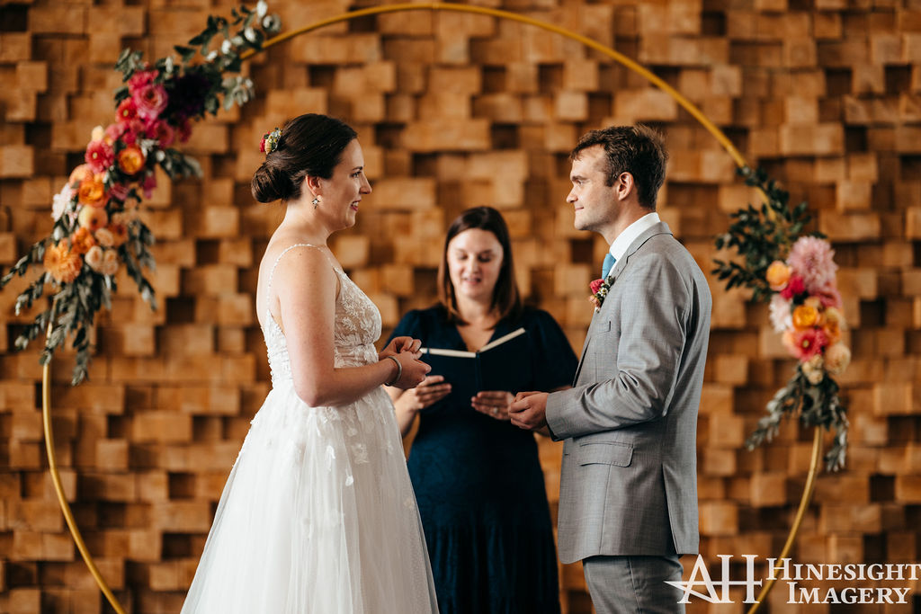 Couple exchanging vows under a circular floral arch