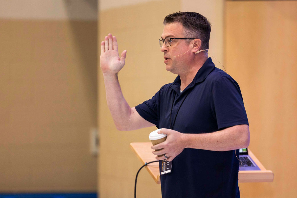 A speaker with his hand raised