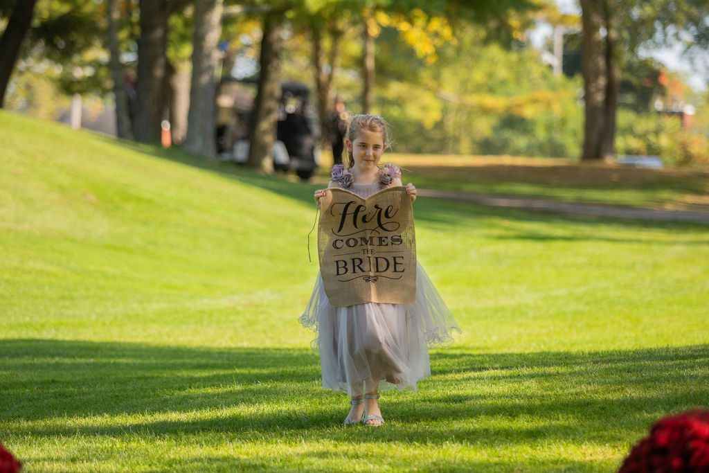 A child carrying a Here Comes the Bride sign