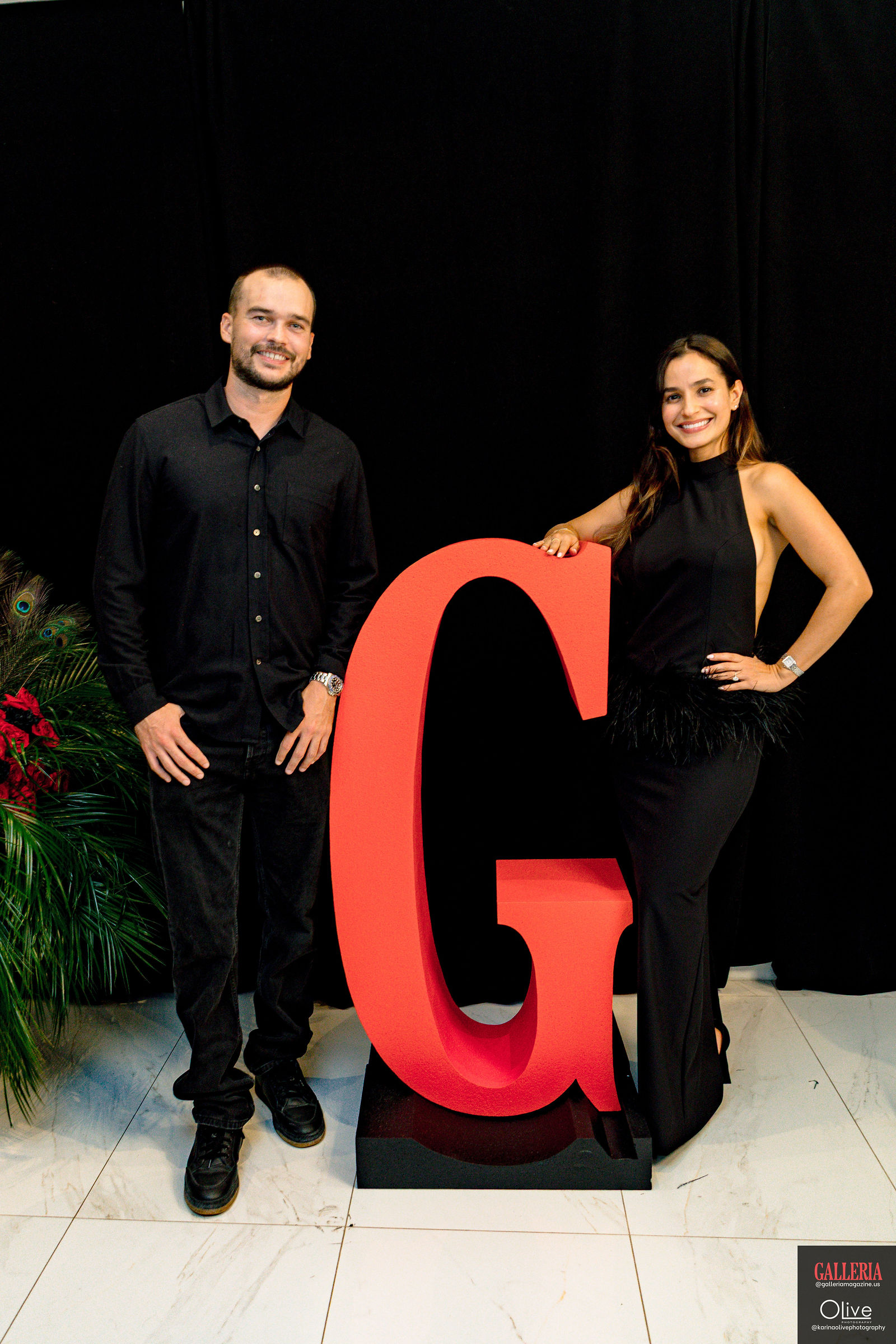 Two guests flanking the red G at the photo backdrop.