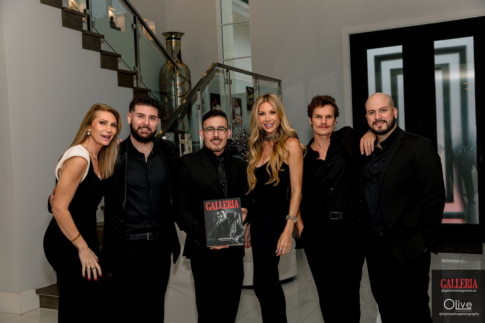 A group of guests gathered at the staircase, one holding the first issue.