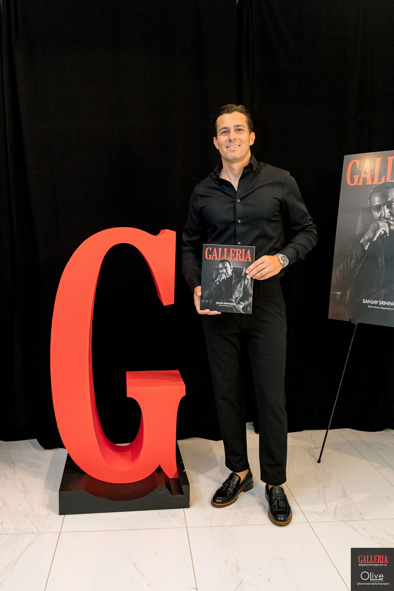 A guest holding up the first print issue beside the red G.