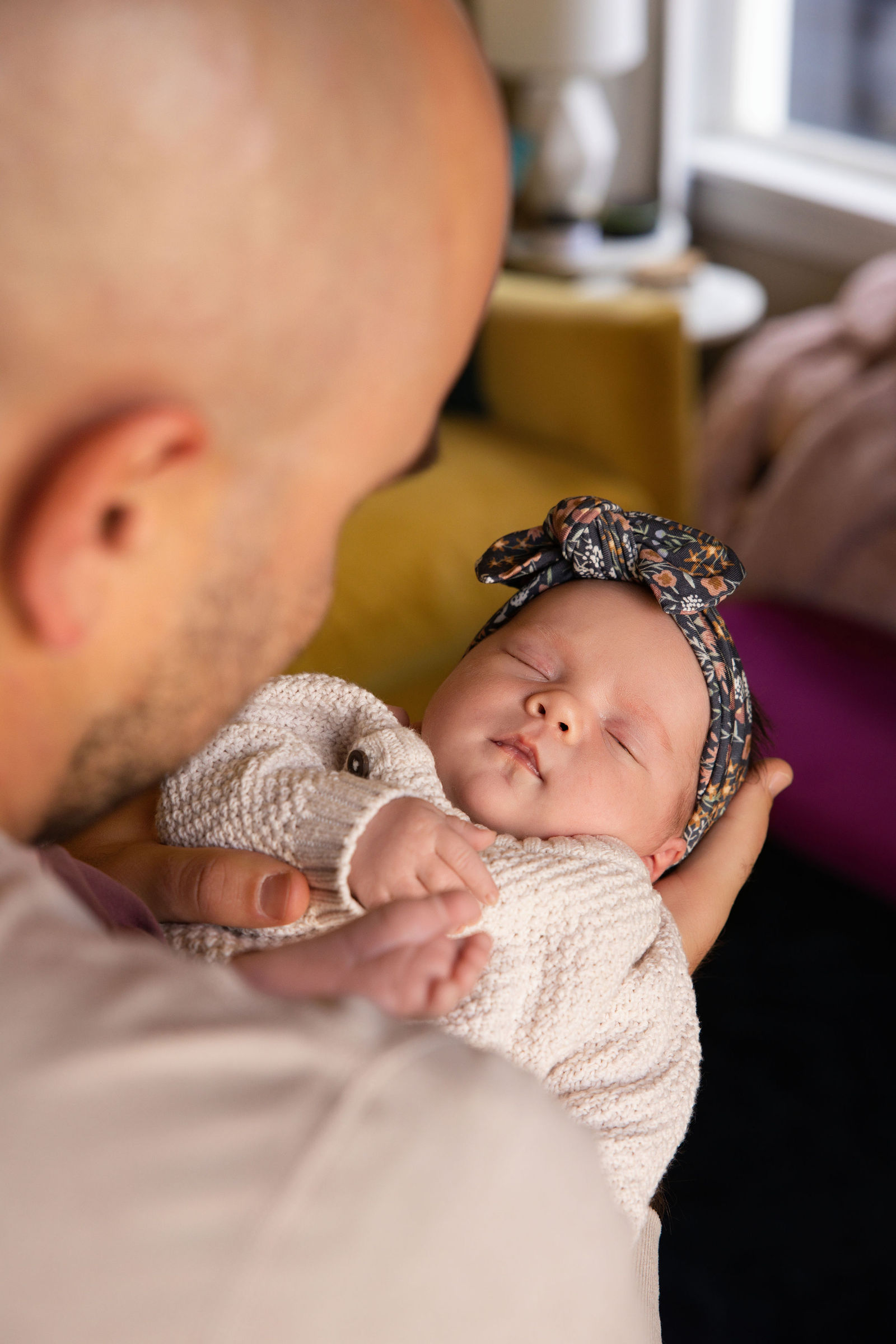 Sibling snuggling newborn on bed during in-home family newborn session