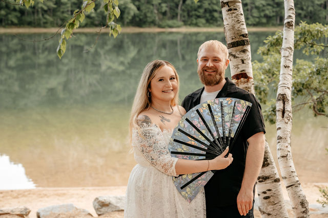 A lush wedding bouquet with the couple kissing in the background