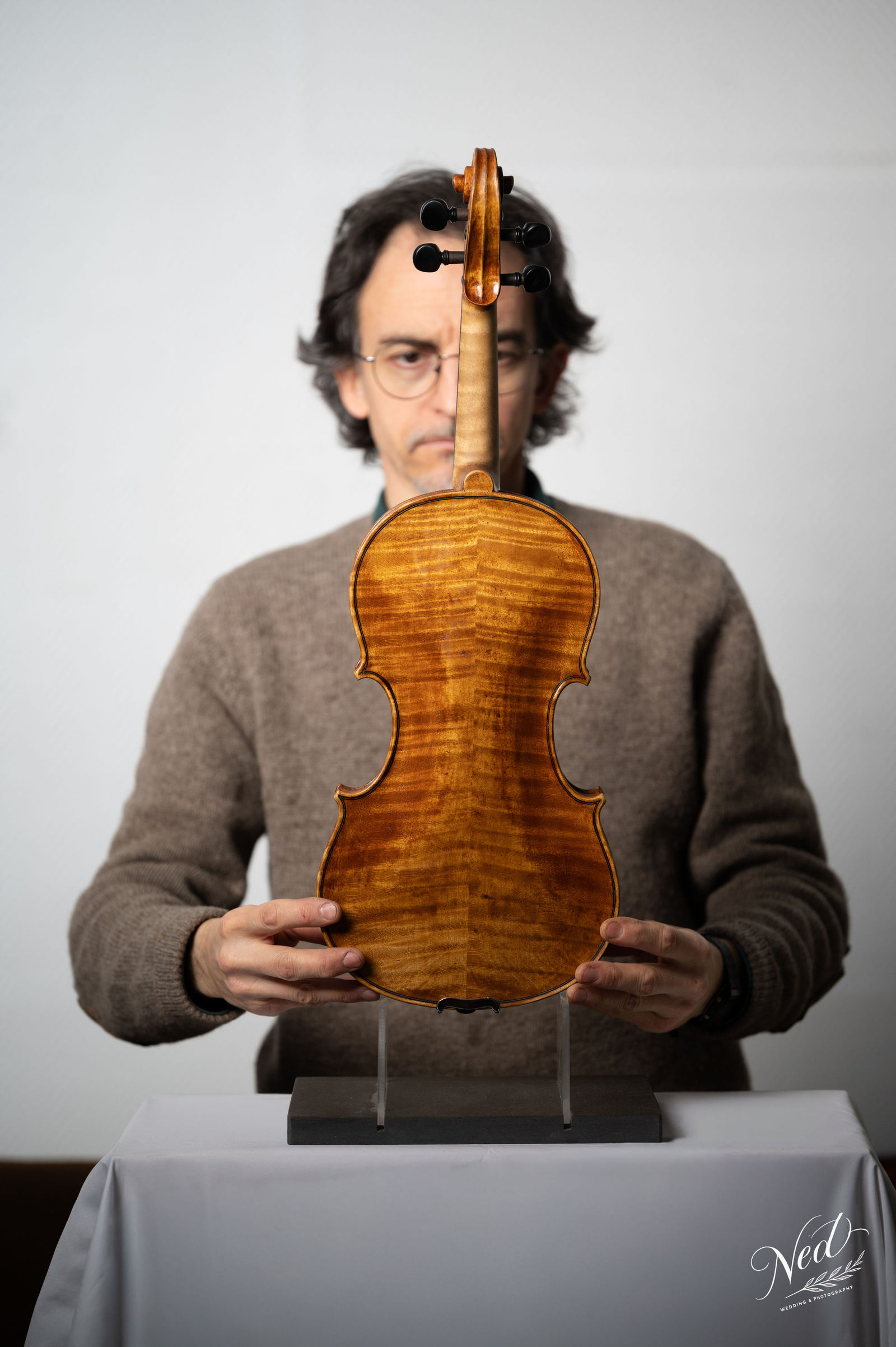 Luthier tenant son violon sur un socle — Portrait artisan