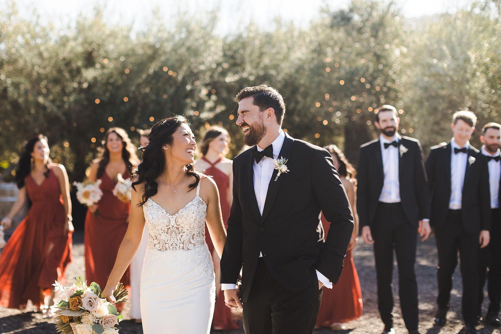 Wedding party laughing together under the olive trees at a Sonoma County wedding