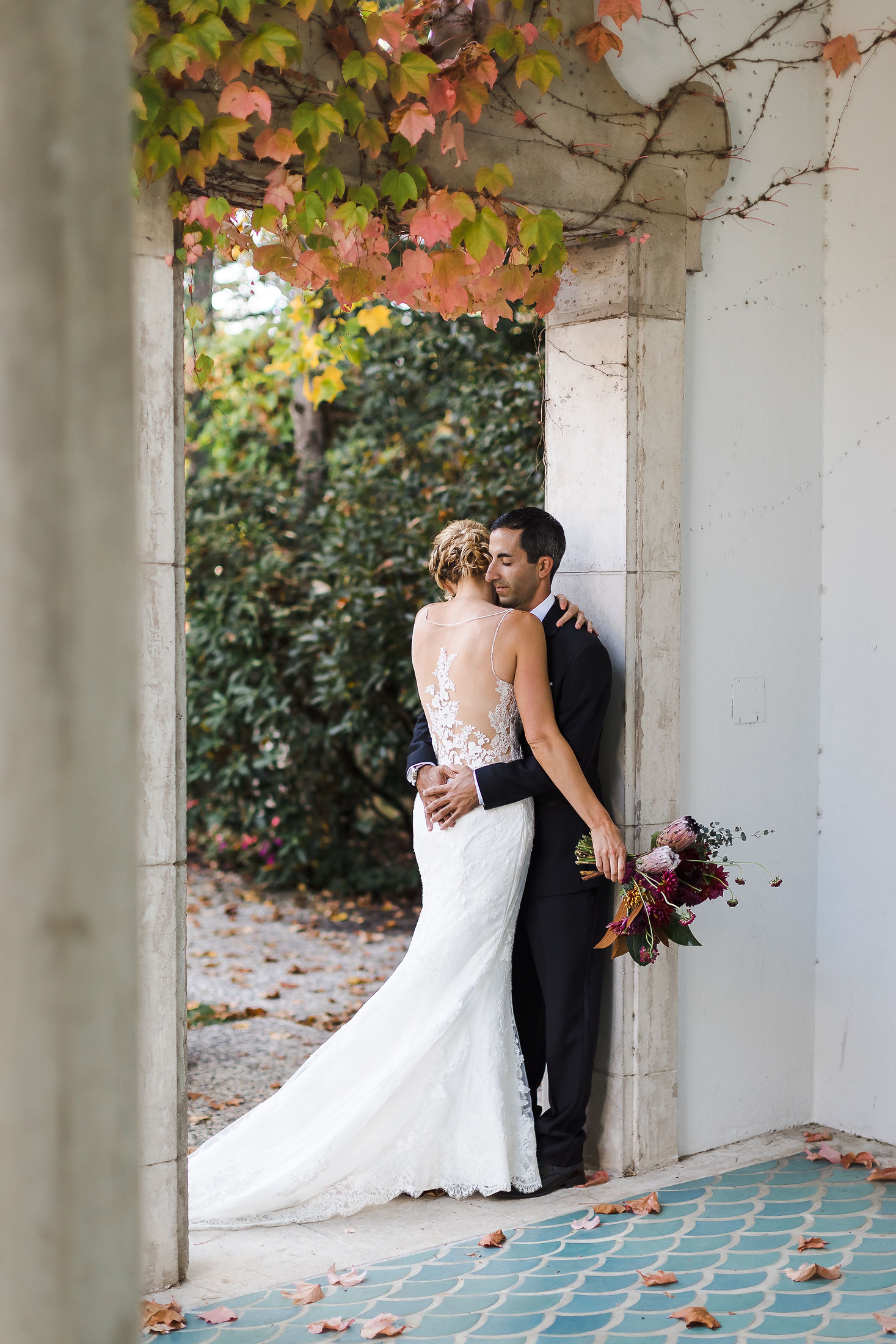Bride and groom embracing beneath a stone archway at a Wine Country wedding