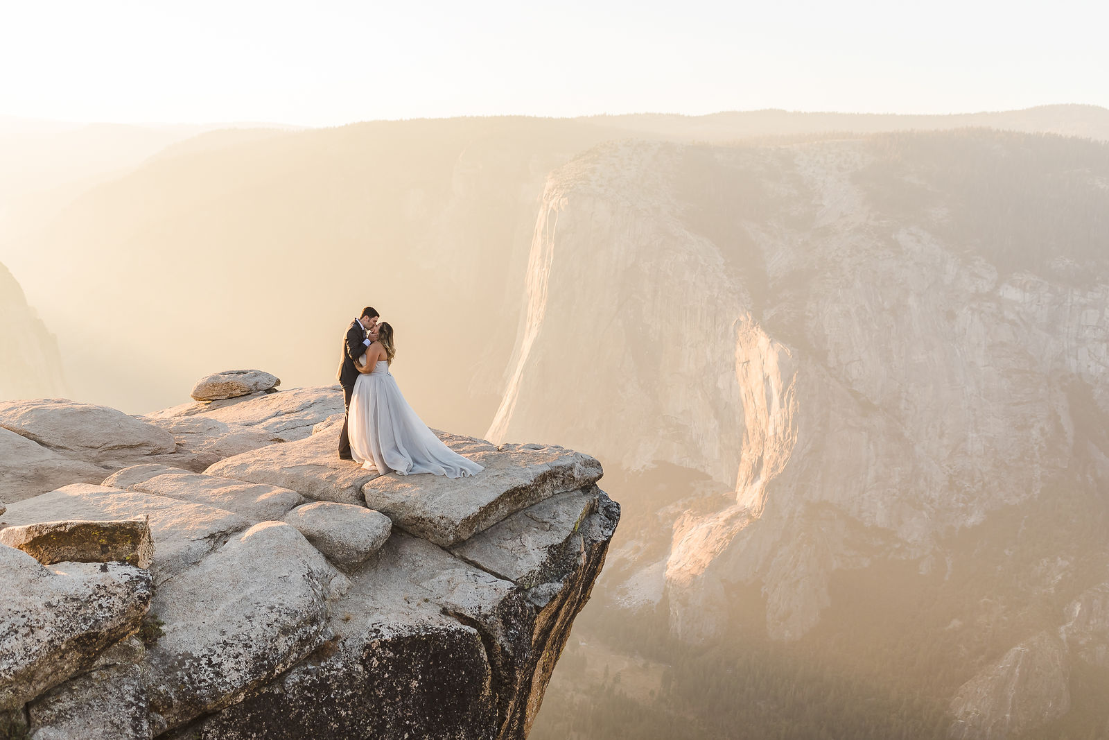 Couple on a cliff edge overlooking the valley at golden hour, wedding photography and film by Kreate