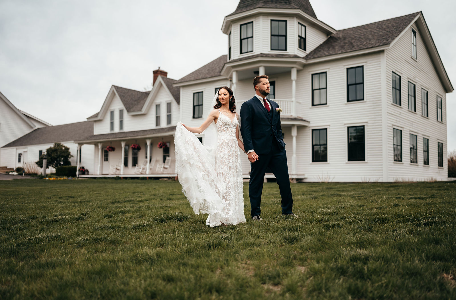 Bride and groom walking across the lawn in front of the manor house at Dell-Lea in Chichester NH