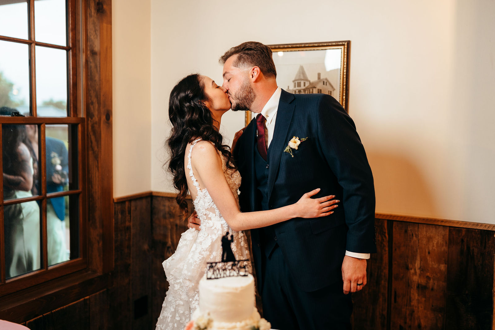 Couple kissing behind their white wedding cake with a Mr and Mrs topper at Dell-Lea