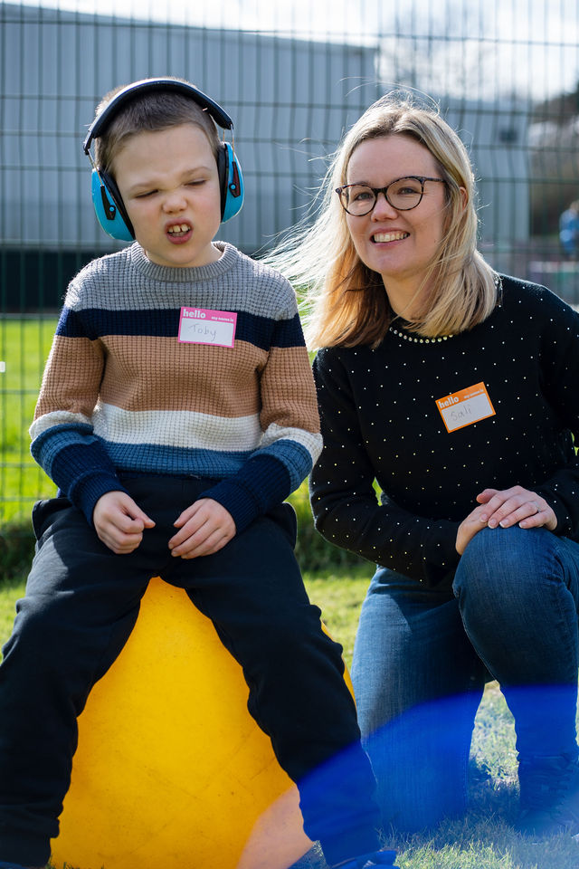 An adult and child sitting together on a yellow space hopper.